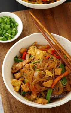 two bowls filled with food and chopsticks on top of a wooden cutting board