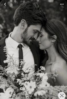 black and white photo of a bride and groom holding flowers in front of the camera