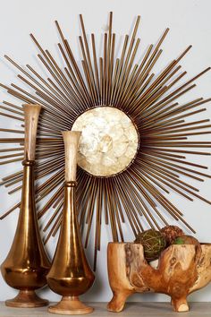 three brass vases sitting next to each other in front of a sunburst