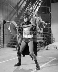 a man dressed as batman holding a barbell