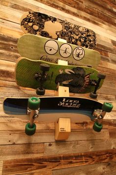 two skateboards are stacked on top of each other in front of a wooden wall