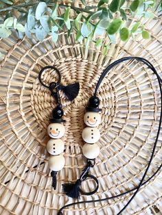 two snowmen are hanging from a wicker basket with black cord and tassels