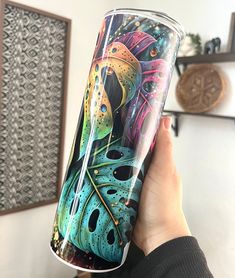 a person holding up a cup with an artistic design on the bottom and inside it