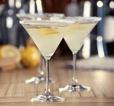 two martini glasses sitting on top of a wooden table