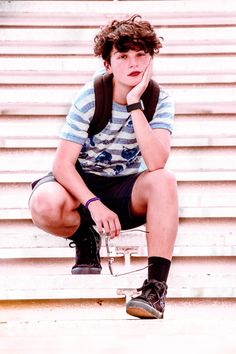 a young man sitting on the steps with his hand under his chin