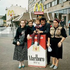 a group of people standing in front of a mcdonald's box with a child on it