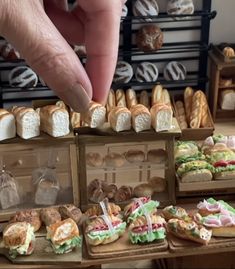 a person is picking up some food from a box on a table in front of other pastries