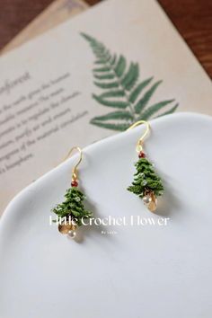 small pine tree earrings on a plate next to an open book