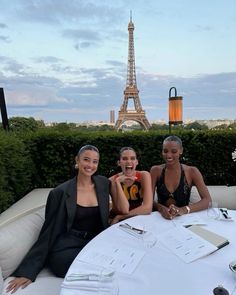 three women sitting at a table in front of the eiffel tower