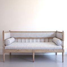 a white couch sitting in front of a wall with two pillows on top of it