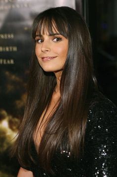 a woman with long brown hair standing in front of a poster