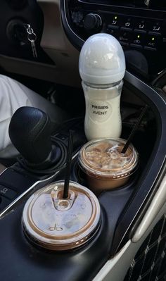 there are two drinks in the cup holder on this car dash board, and one is empty