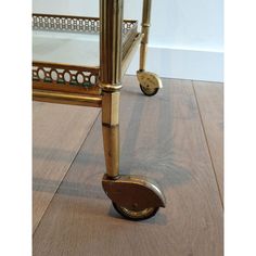 an antique brass bed frame with wheels and foot rests on the floor in front of a mirror