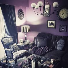 a living room with purple walls and black furniture