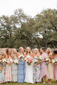 a group of women standing next to each other holding bouquets in their hands and laughing