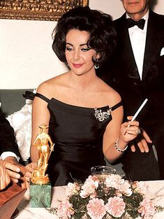 a man and woman sitting at a table with an award