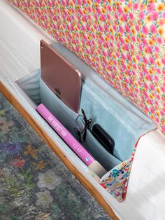 an open laptop computer sitting on top of a wooden desk next to a flowered headboard