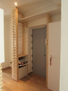 an empty room with wooden slats on the wall and door to another room in the background