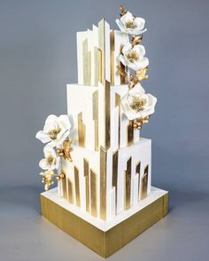 a tall white and gold building with flowers on the top, against a gray background