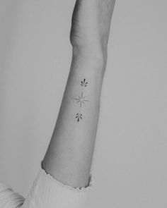 a black and white photo of a person's arm with a small tattoo on it