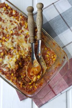 a casserole dish with meat and vegetables in it next to a serving spoon