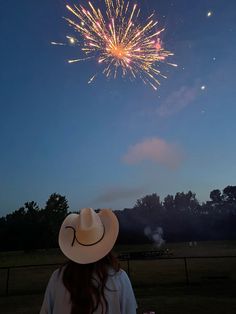 a woman wearing a cowboy hat watching fireworks