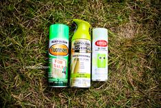 three spray cans are laying on the grass