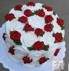 a cake with white and red roses on top is sitting on a plate, ready to be eaten