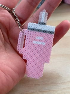 a hand holding a pink keychain that has a small pixelated object on it