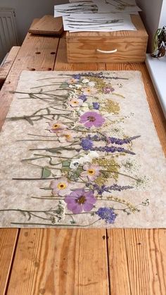 a wooden table topped with a rug covered in flowers