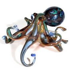 an octopus sculpture sitting on top of a white table next to a blue glass ball