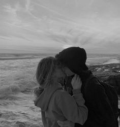 two people standing next to each other near the ocean