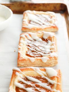 some kind of pastry with icing on top of it sitting on a baking sheet