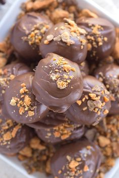 chocolate covered donuts in a white container with sprinkles and nuts on top