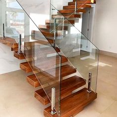 a stair case with glass railing and wooden handrails in a modern style home