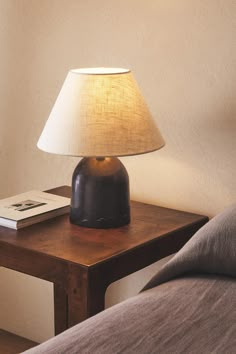 a lamp on a table next to a bed