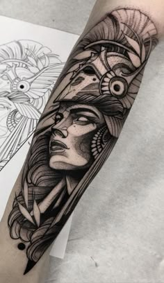 a woman's arm with an egyptian mask tattoo on the left side of her body