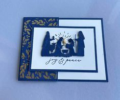 two christmas cards with the words joy and peace in gold foil on blue paper, sitting next to each other