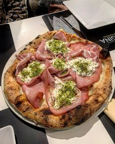 a pizza with meat and cheese on it sitting on a table