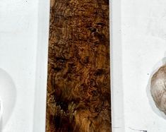 a piece of wood sitting on top of a white wall next to a stone vase