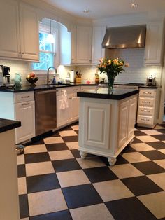 a kitchen with black and white checkered flooring, stainless steel appliances and an island