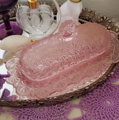 a pink glass dish sitting on top of a table next to other items in a basket