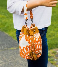 an orange and white purse with tassels hanging from it's shoulder strap