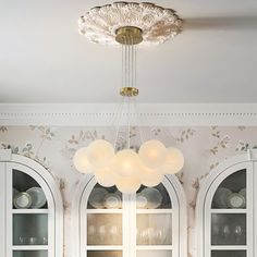 a dining room table with white chairs and china cabinet in the corner between two windows