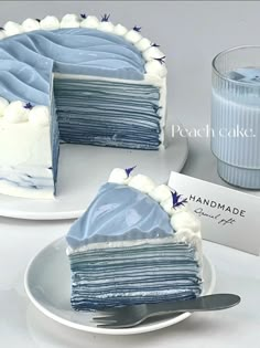 a blue cake with white frosting on a plate next to a glass of water