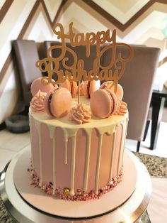 a birthday cake is decorated with pink icing and gold lettering that says happy birthday