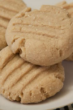 three peanut butter cookies stacked on top of each other in front of a white plate