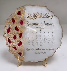 a white and gold plate with red flowers on it is next to a calendar that reads sagmni & iman