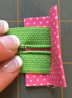 a hand holding a pink and green piece of fabric