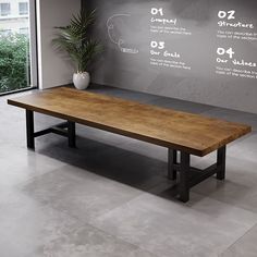 a large wooden table sitting in front of a window next to a potted plant